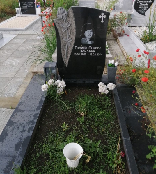 Цвят на роза с дръжка и листа върху паметник от черен гранит