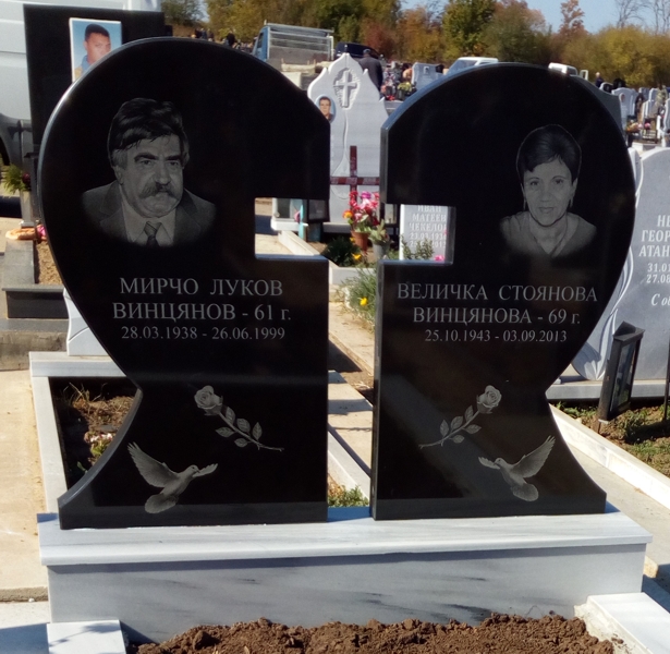 Надгробен паметник сърце с въздушен кръст от две плочи черен гранит, с гравирани портрети, надписи, гълъби и рози, повдигната кутия и облицовани бордюри от светлосив мрамор, пътека от светлосив термолющен гранит, кръгла стругована ваза от черен гранит, аранжировка с черна мозайка.