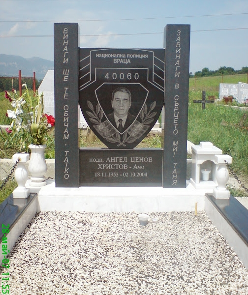 Паметник от черен гранит с дебелина 15 см и 8 см, с формата на полицейска значка, с гравиран портрет и надписи, облицован бордюр от бял мрамор и черен гранит, ограждение от декоративни балюстри със верига, ваза и фенер.