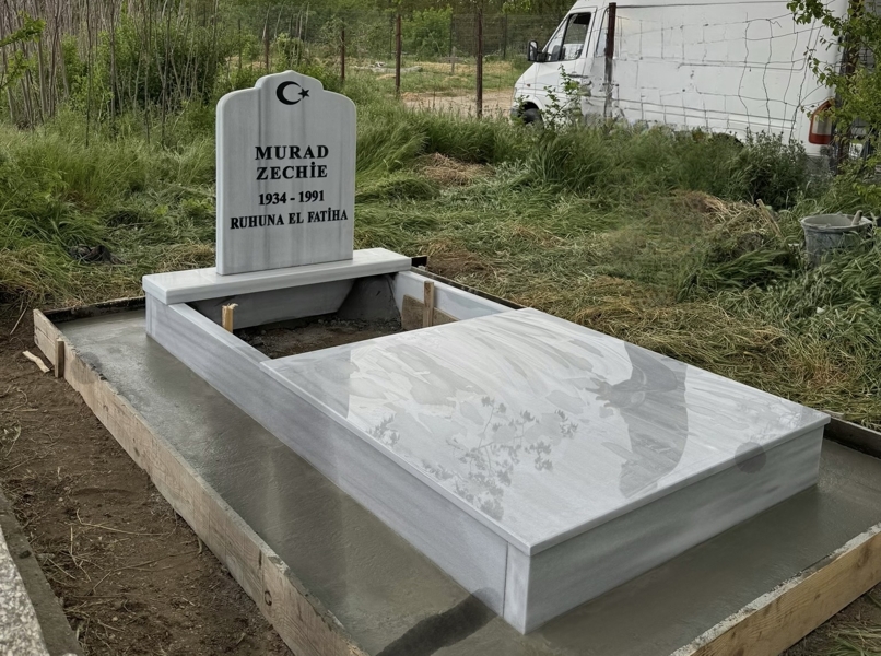 Мюсюлмански паметник с полумесец и звезда, надпис с вдълбани черни букви, постамент, висок масивен бордюр, покривна плоча до средата, циментова пътека, бетонна основа