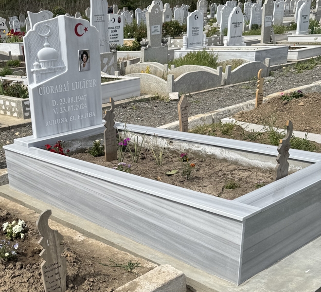 Мюсюлмански паметник с полумесец и звезда, цветна правоъгълна порцеланова снимка, надпис с вдълбани бели букви, постамент, висок облицован бордюр, бетонна основа, изглед отляво