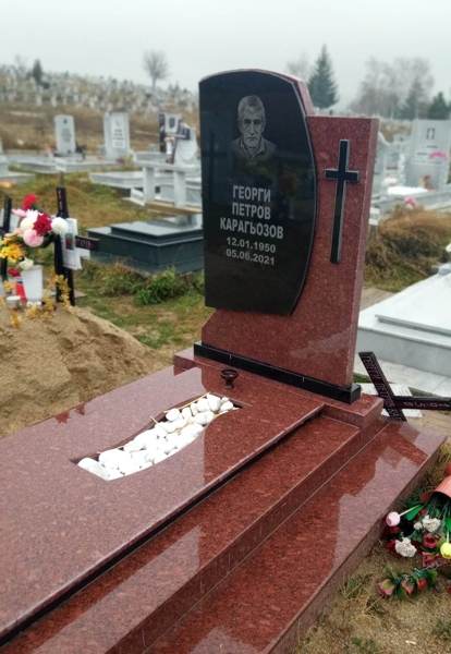 Плоча от червен гранит Империал, раздвижен италиански модел, с гравиран портрет и надпис върху залепена черна плоча, залепен черен кръст, червена покривна плоча с чела от черен гранит, с изрязан отвор, запълнен с овални едри бели декоративни камъни, два постамента - черен и червен, червени пътеки на две нива. Изглед отстрани.