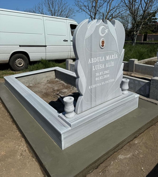 Monument musulman cu semilună și stea, fotografie eliptică colorată din porțelan, inscripție cu litere albe sculptate, două vaze rotunde, piedestal, bordură înaltă cu gresie, alee de beton, bază de beton, vedere a fațadei monumentului